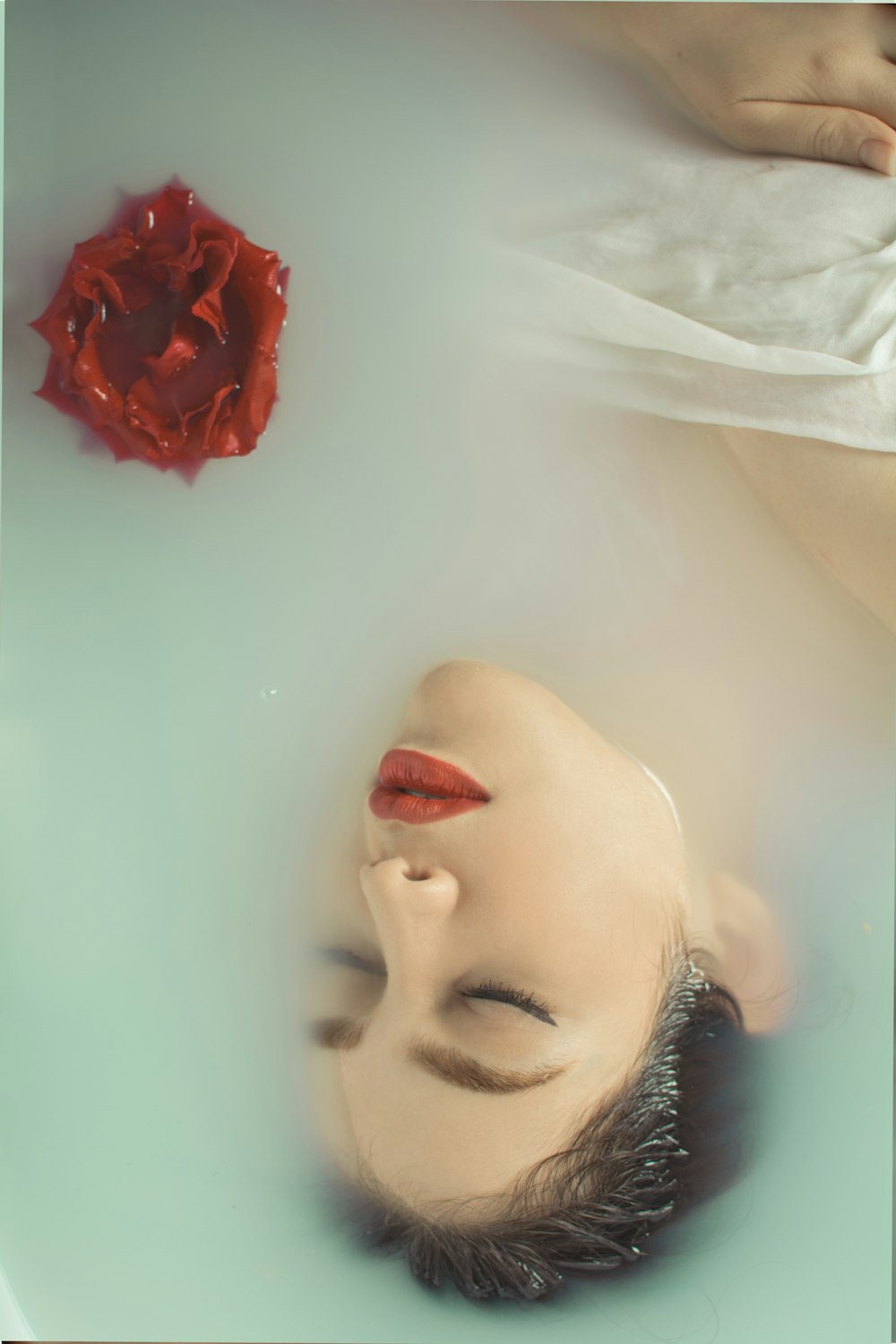 a woman laying in a bathtub with a red rose