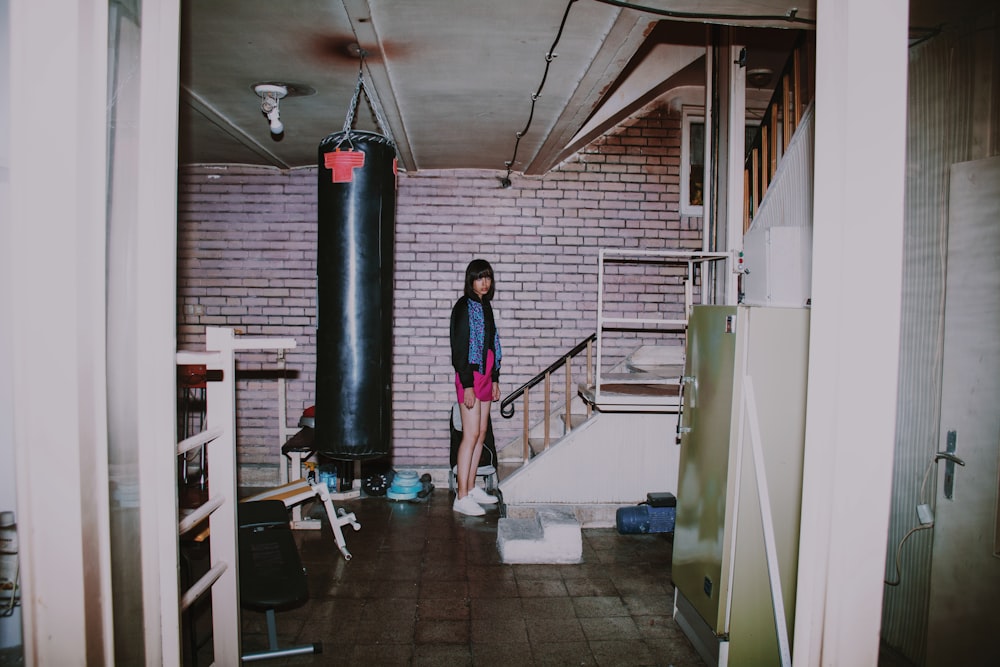 a woman standing next to a punching bag