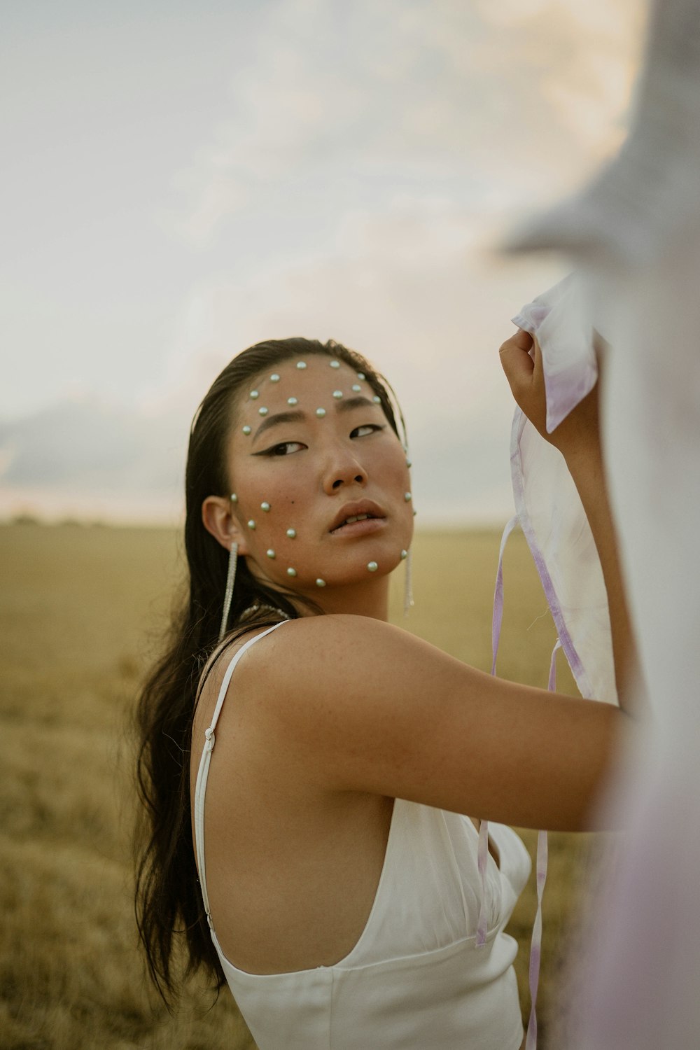 a woman standing in a field holding a piece of cloth