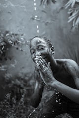 A candid portrait of a child laughing under a rain shower, droplets sparkling in sunlight.