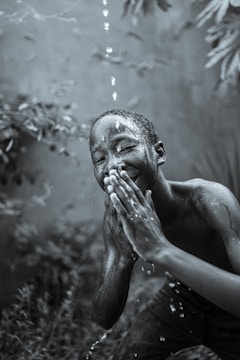 A candid portrait of a child laughing under a rain shower, droplets sparkling in sunlight.