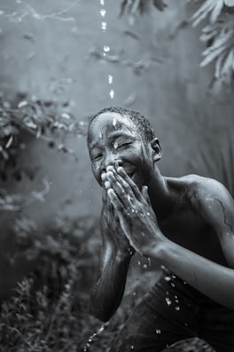 Children laughing and playing with water in a gentle stream during a nature-inspired event.