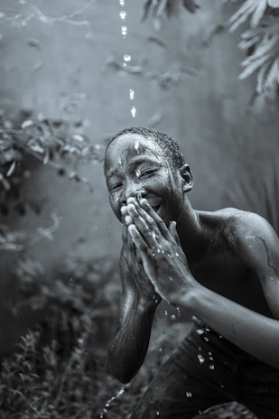 Close-up of a joyful child playing with water droplets in a lively Indian village.
