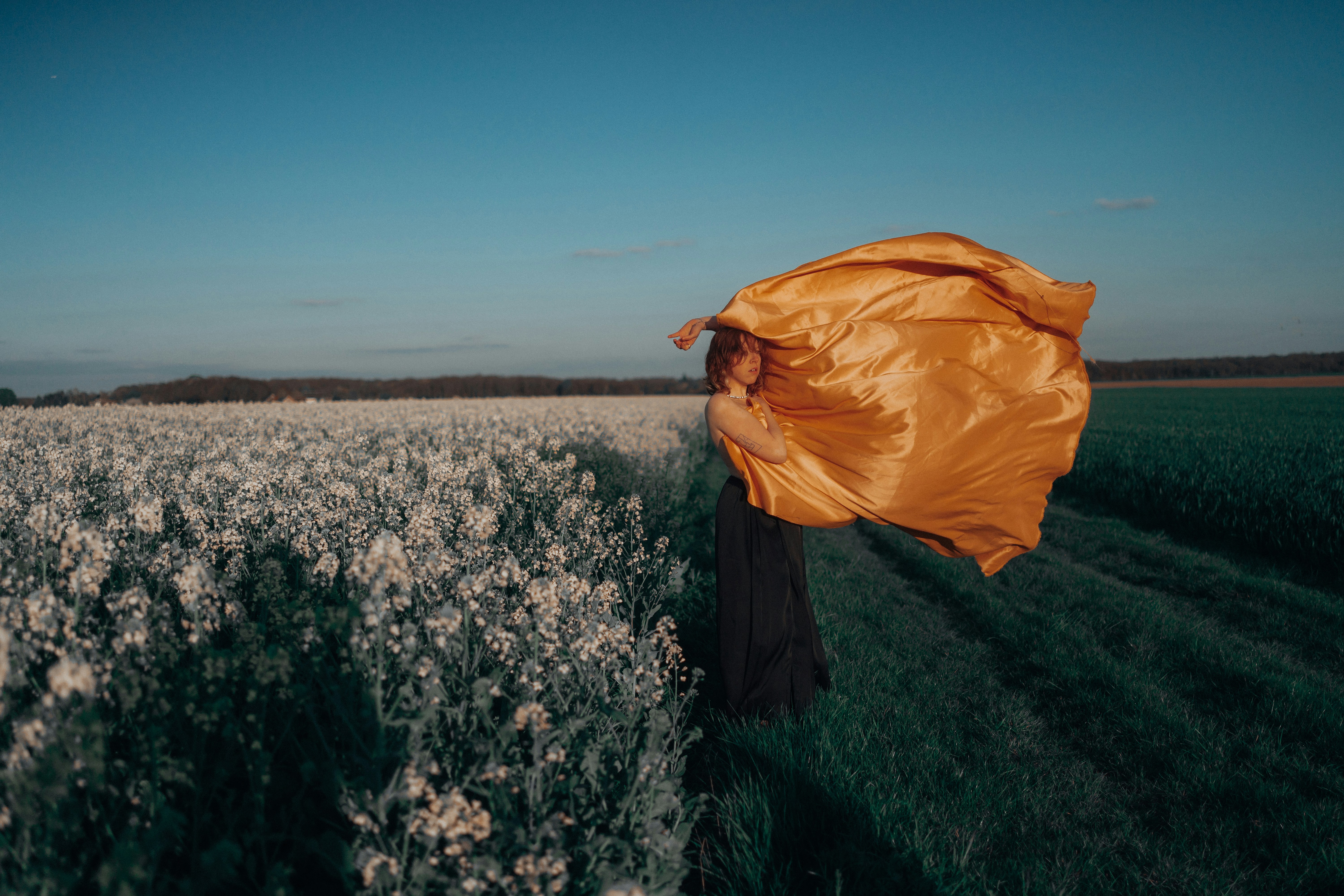 a woman standing in a field holding a yellow cloth