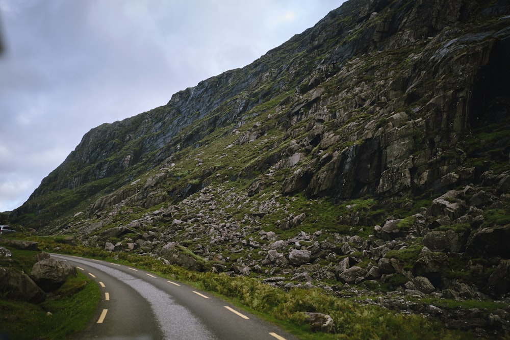 a car driving down a road next to a mountain