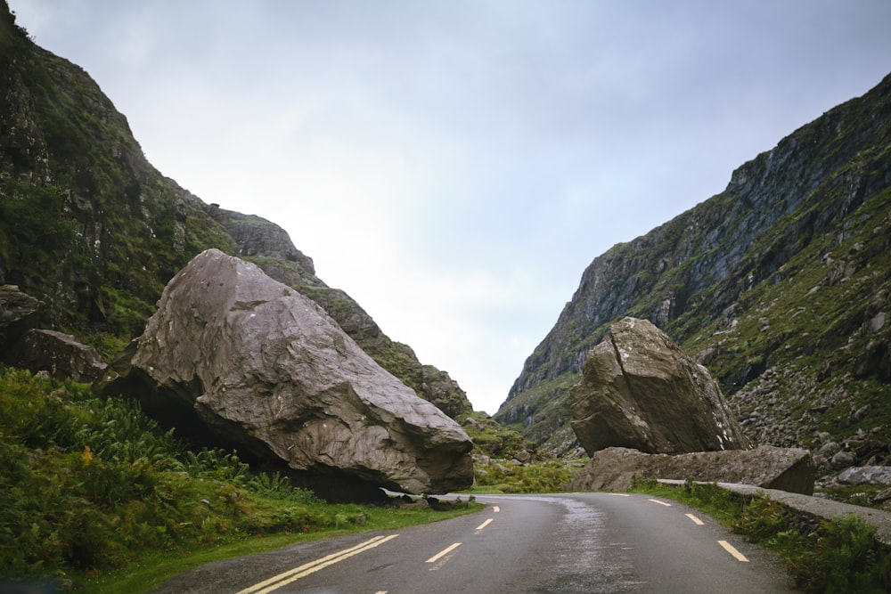 a car driving down a road next to large rocks