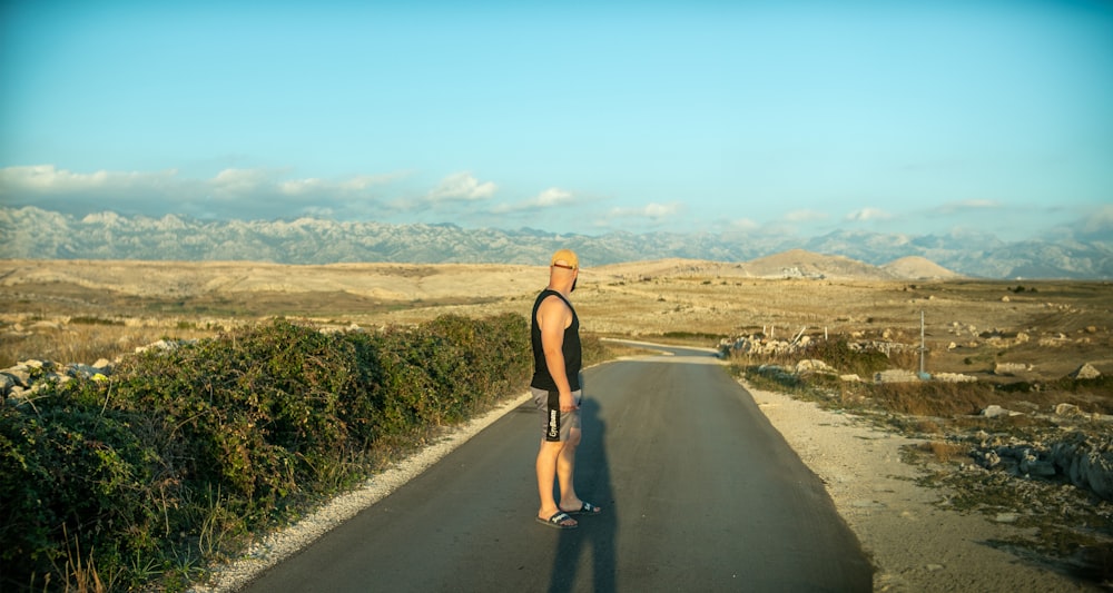 a man standing on the side of a road holding a skateboard