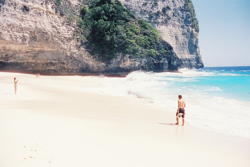 a couple of people standing on top of a sandy beach