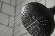 The sproos shower head in vibrant matte black, water flowing softly from its nozzles.