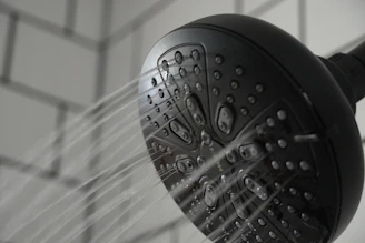 Close-up of a precision-engineered water-saving device installed on a modern showerhead in a hotel bathroom.