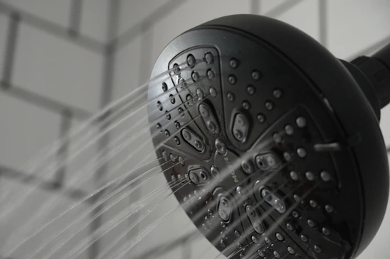 Close-up of a precision-engineered water-saving device installed on a modern showerhead in a hotel bathroom.