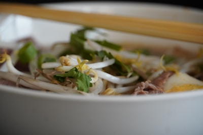 A vibrant bowl of pho with fresh herbs and steam rising, capturing the essence of Vietnamese street food.