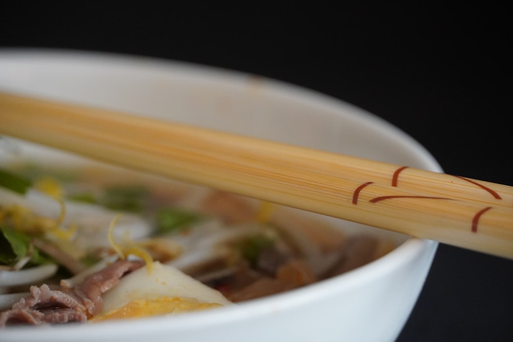 a close up of a bowl of food with chopsticks