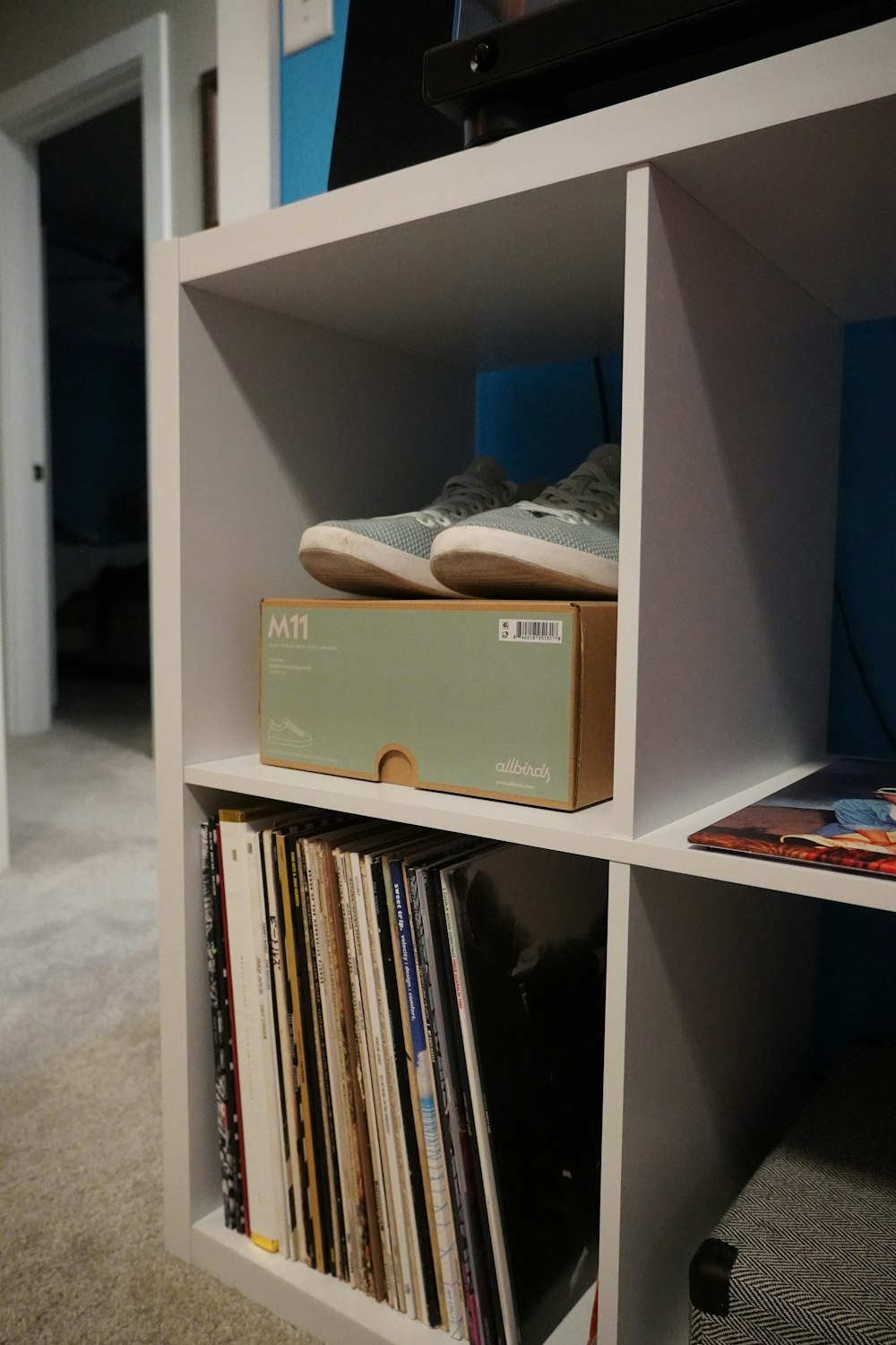 a white shelf with a box and some records on top of it