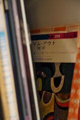 A collection of vinyl records lined up on a shelf, with the visible cover showing a detailed abstract design and the title 'Time Out' alongside some Japanese text. The cover also mentions 'Stereo' and the artist.