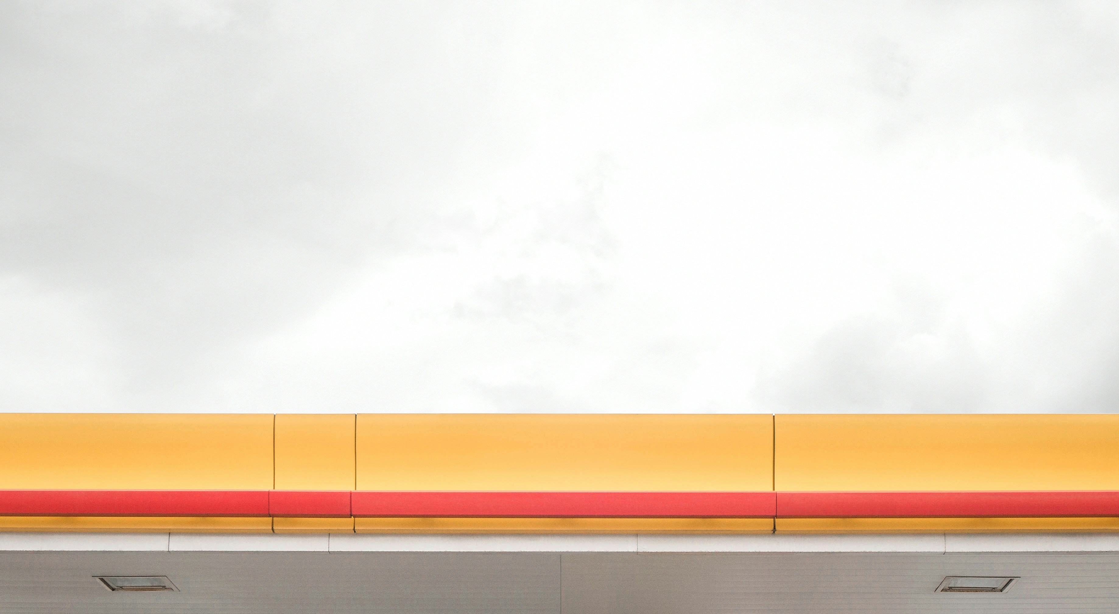a red and yellow bench sitting under a cloudy sky