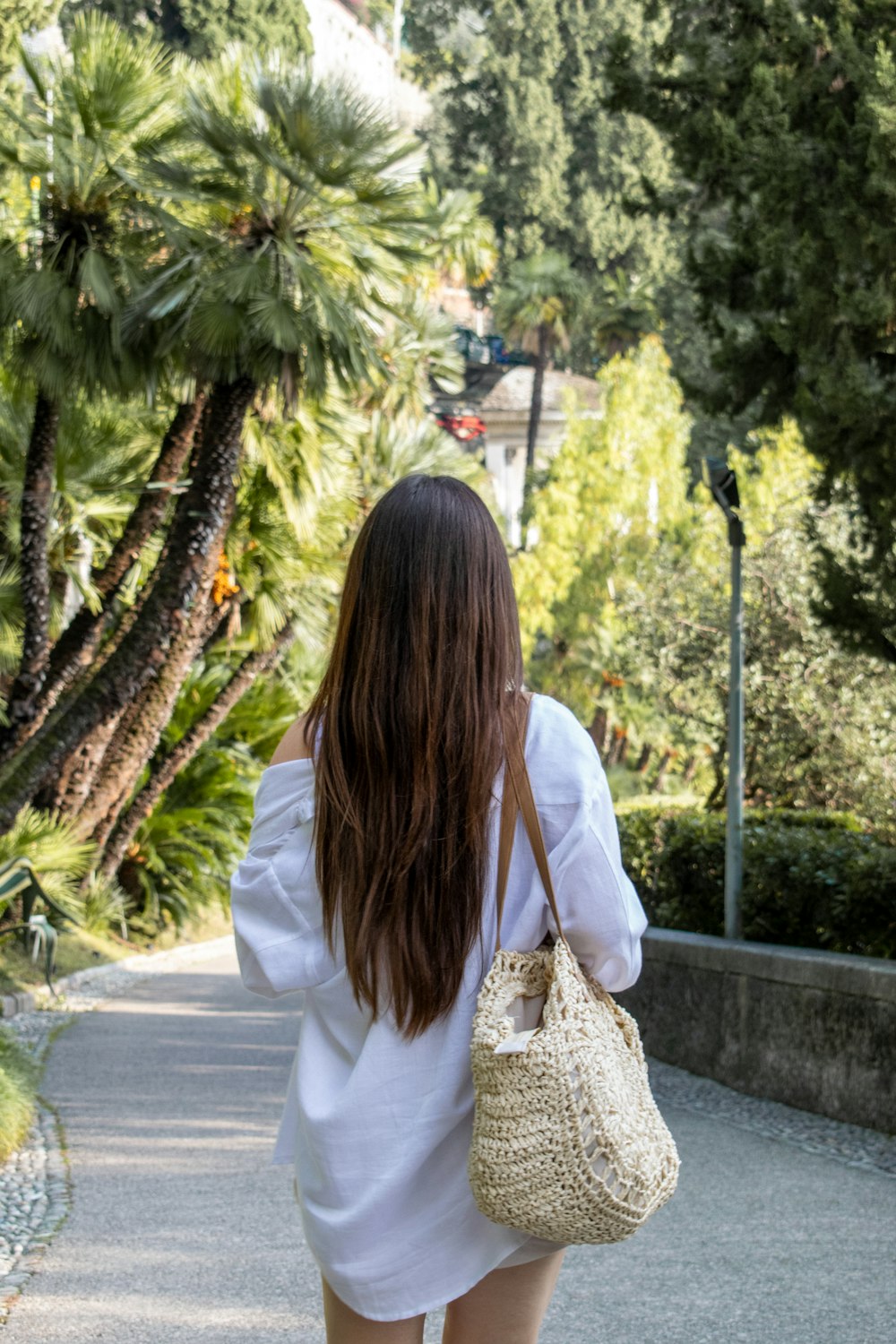 a woman walking down a sidewalk carrying a purse