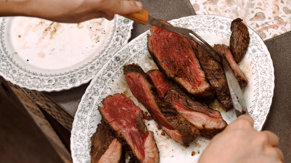 a person cutting up some meat on a plate