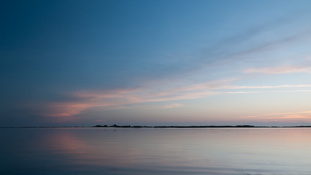 a large body of water with a sky in the background