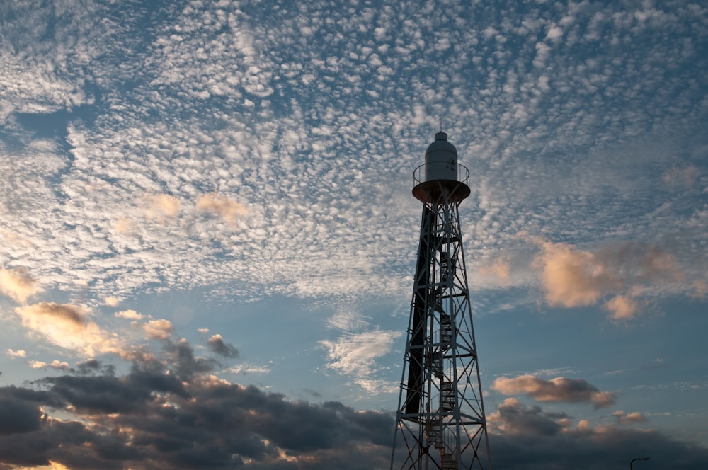 a tower with a light on top of it under a cloudy sky