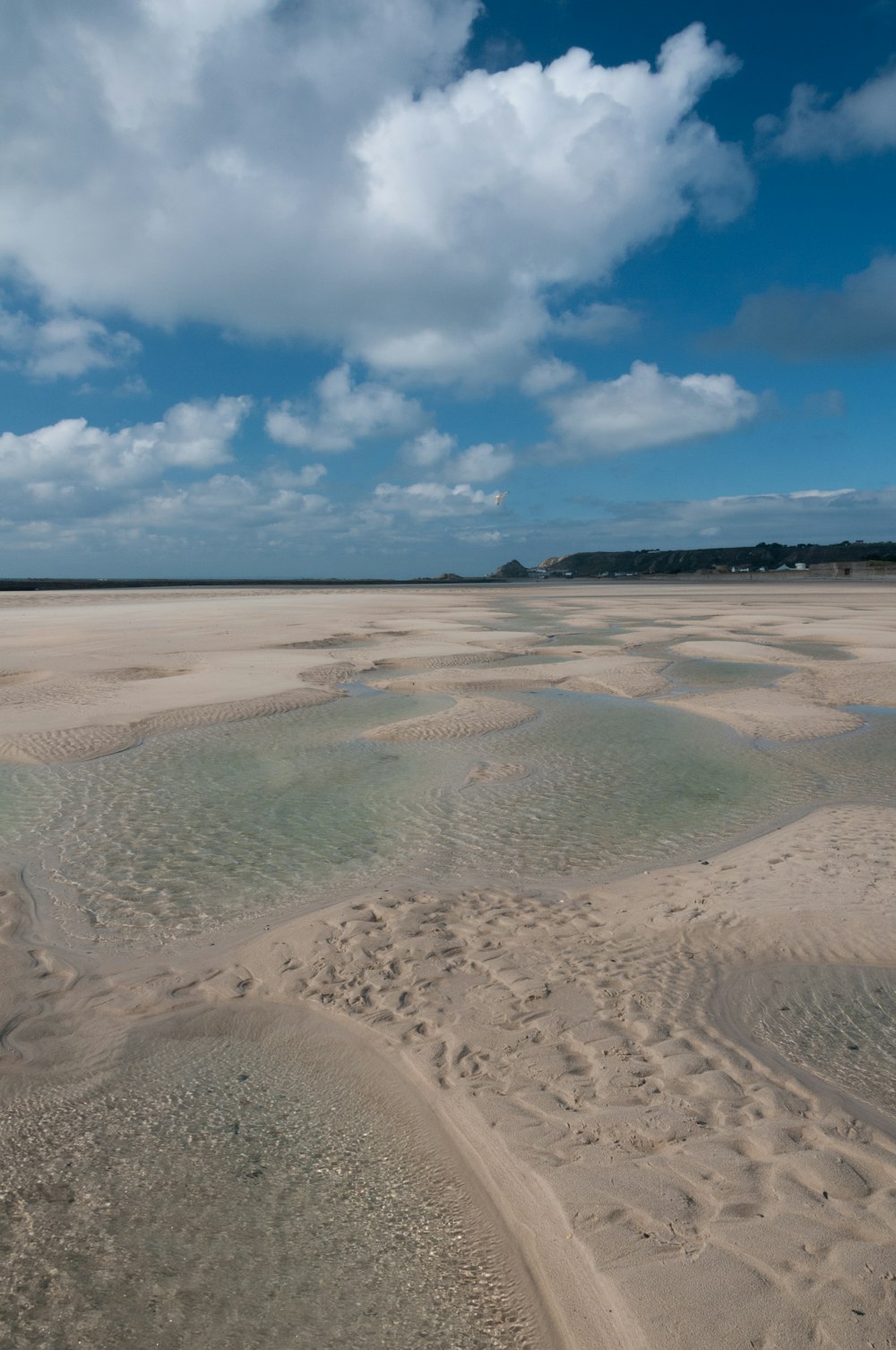 una playa de arena con un cuerpo de agua en el medio