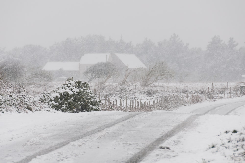 a snow covered road with a house in the background