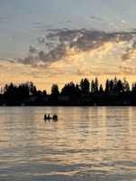 A family enjoying a peaceful sunset by a serene lake during a guided tour.