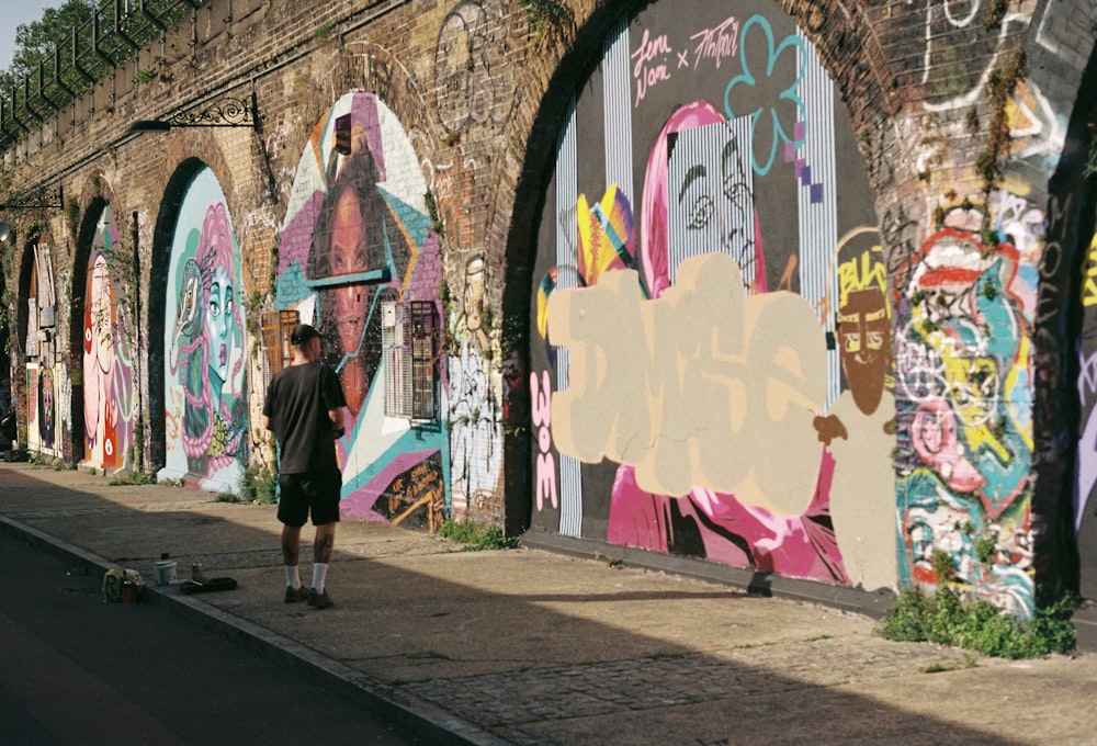 a man standing next to a wall covered in graffiti