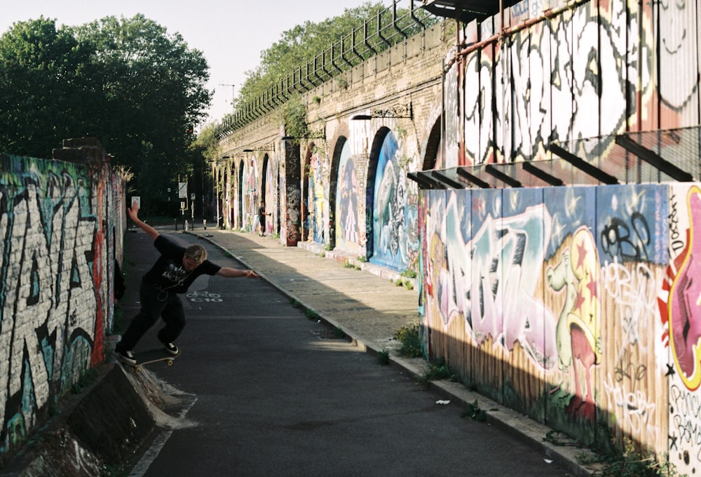 a man riding a skateboard down the side of a wall covered in graffiti