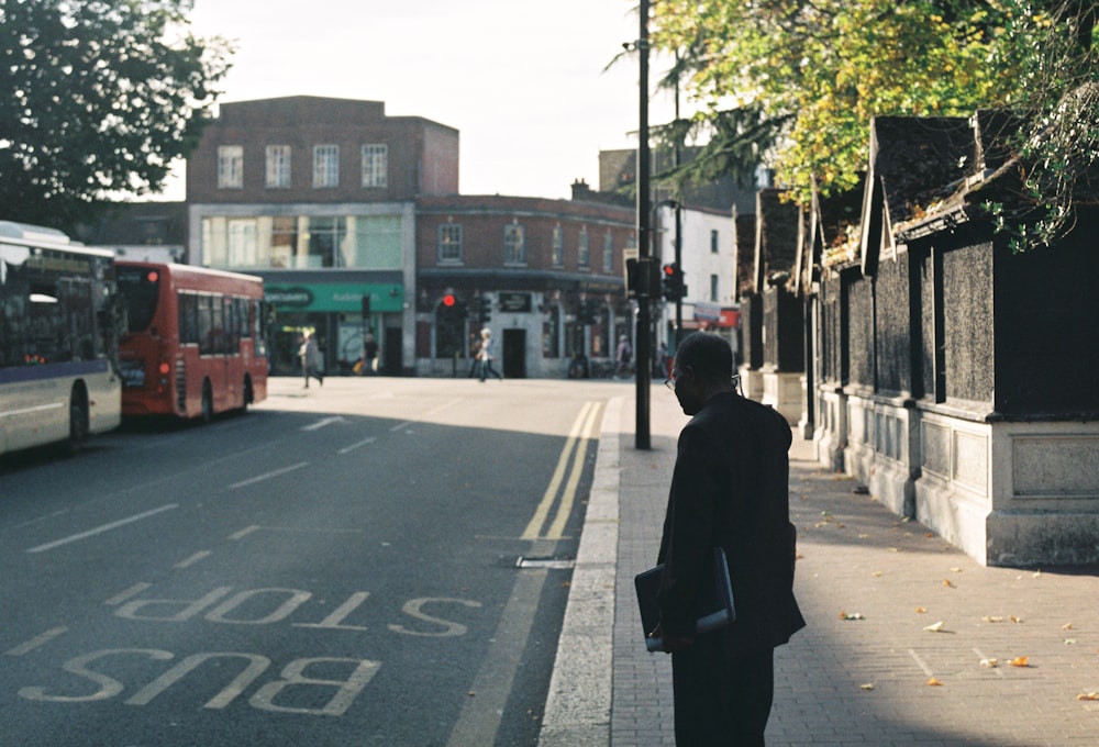 a man standing on the side of a street next to a bus