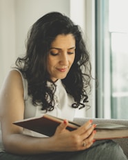 a woman sitting on a couch reading a book