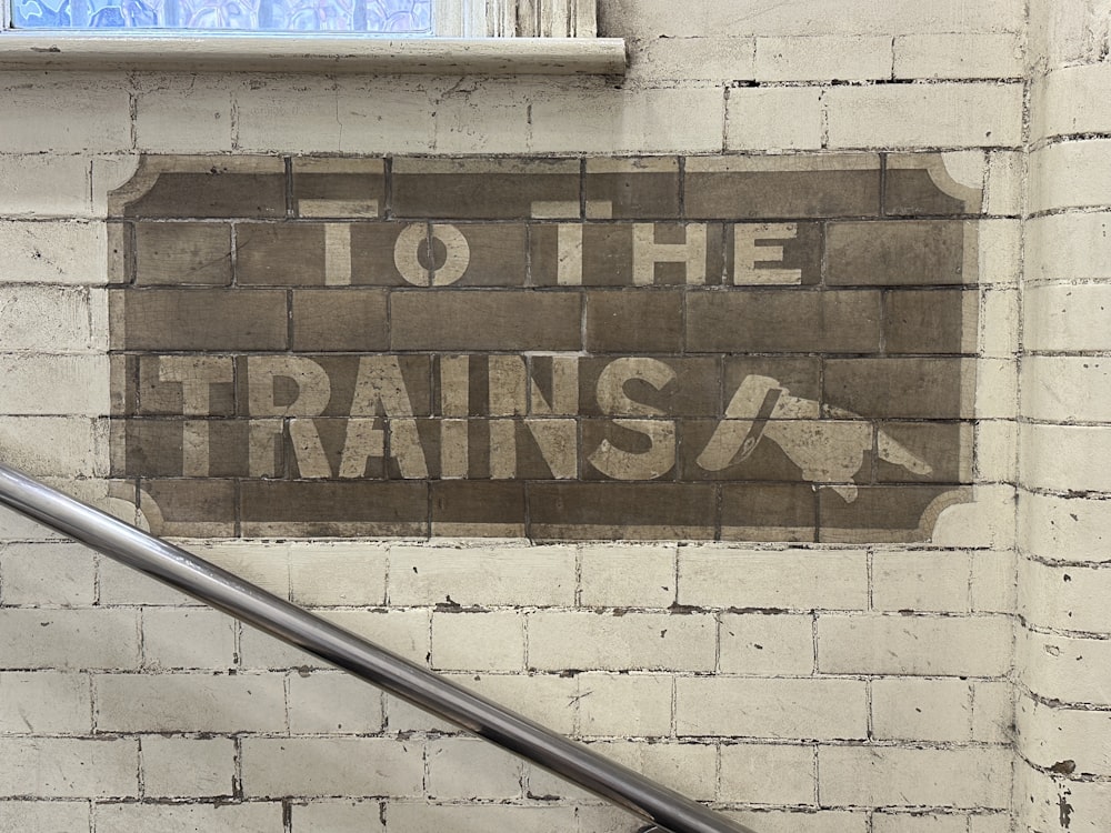 a sign on a brick wall that says to the trains