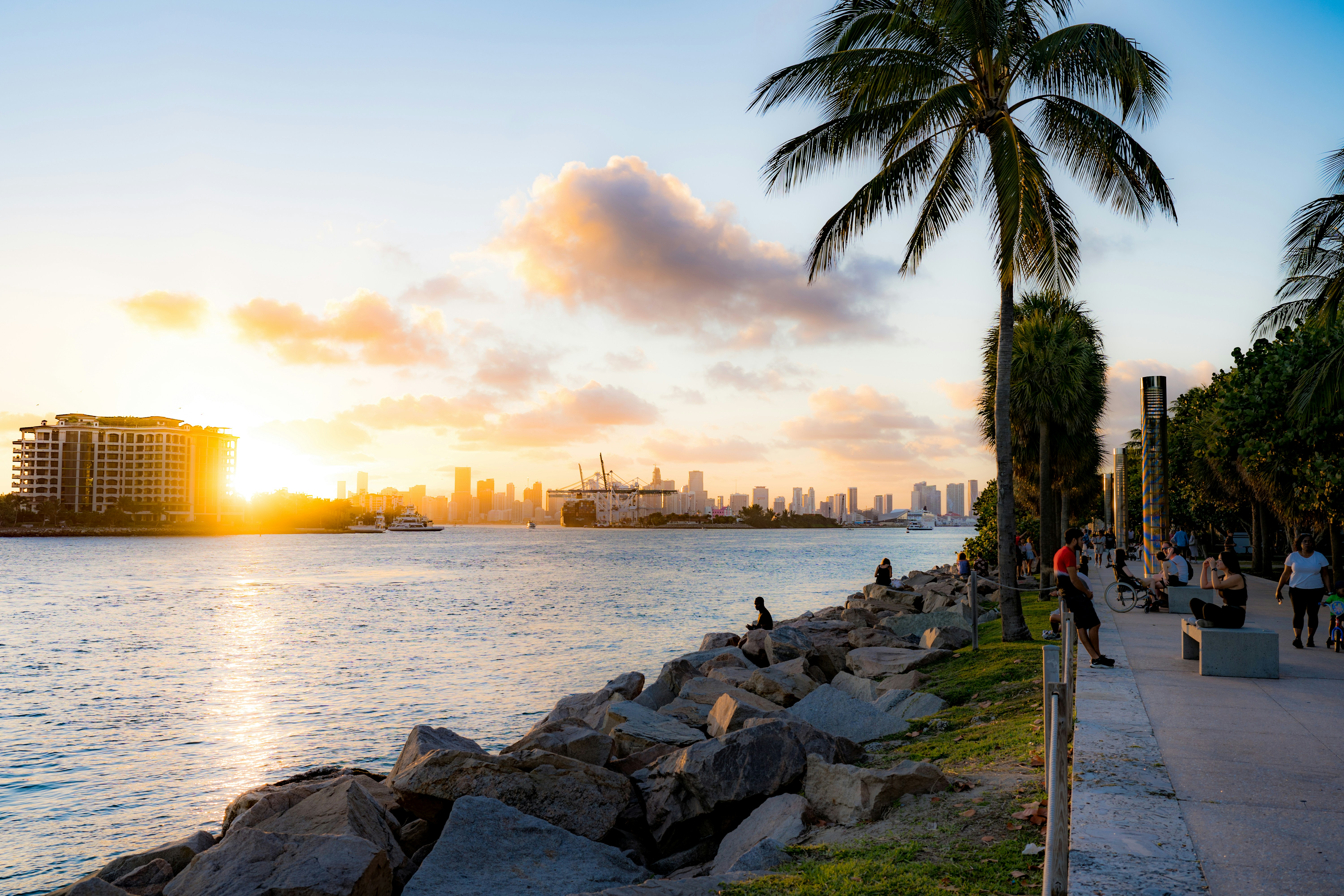 people walking on a sidewalk next to a body of water