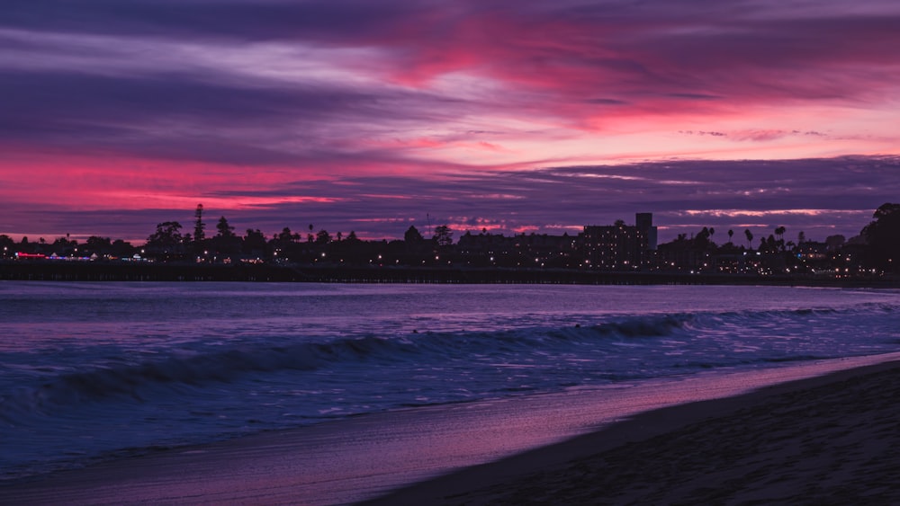 a sunset view of a beach with a city in the background