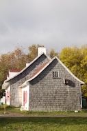 a gray house with a red door and windows