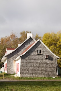 a gray house with a red door and windows