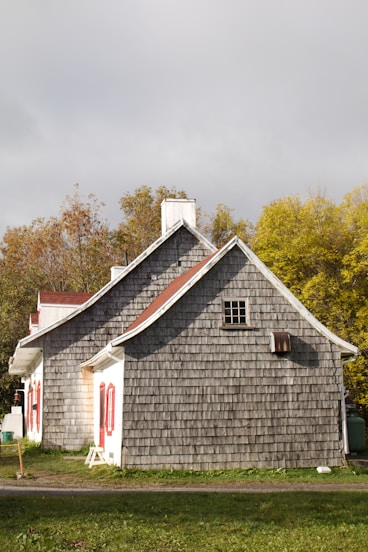 a gray house with a red door and windows