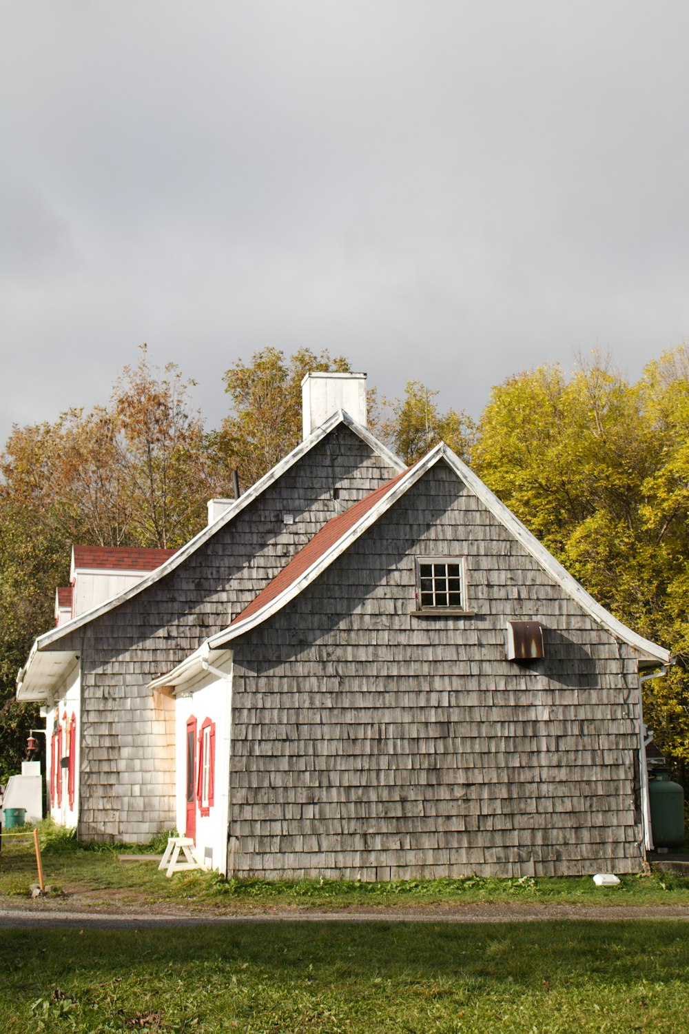 a gray house with a red door and windows