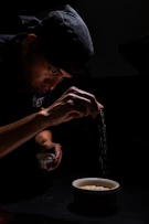 a man in a black shirt is sprinkling noodles