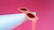 A pair of stylish, translucent pink sunglasses rests atop a white cylindrical object, set against a vibrant pink background. The sunglasses have a retro feel, with oversized frames and dark lenses.