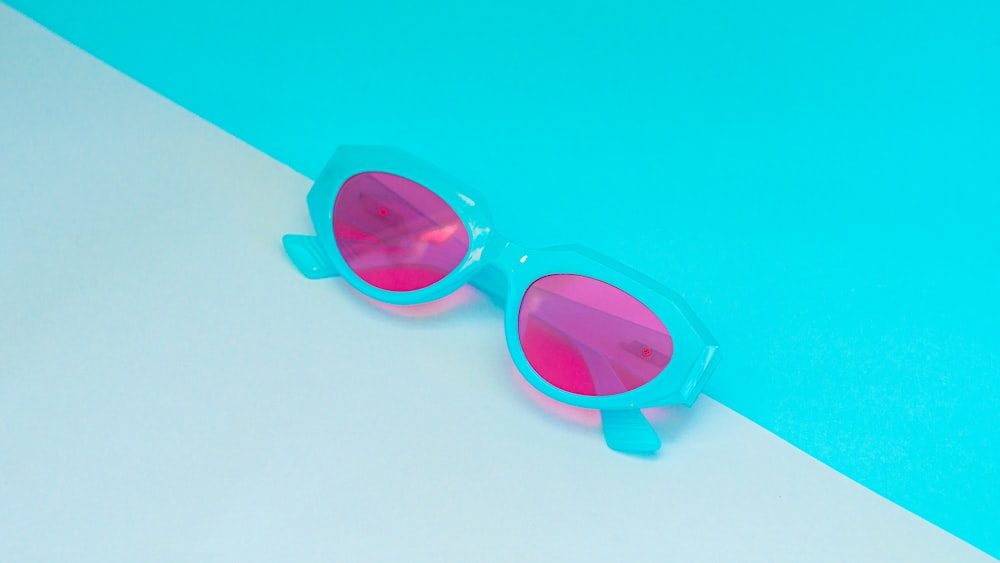 a pair of pink and blue sunglasses on a blue and white background