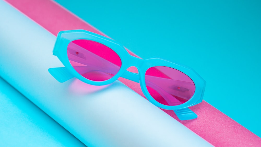 um par de óculos de sol cor-de-rosa sentado em cima de um rolo de papel