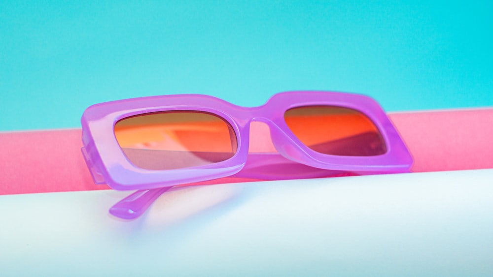 a pair of purple sunglasses sitting on top of a pink and white pole