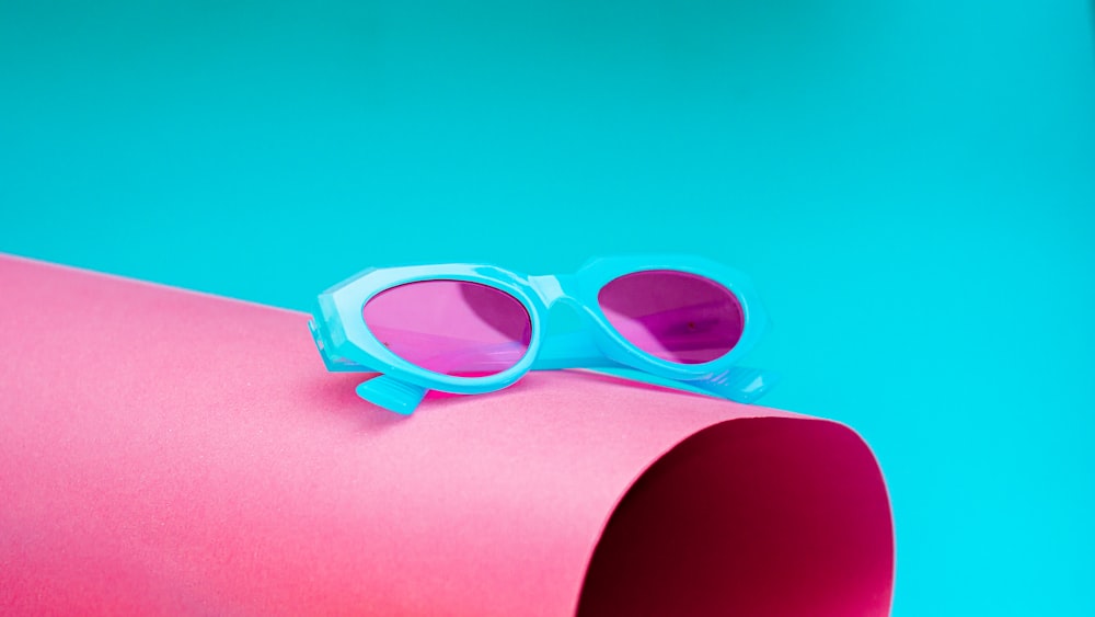 a pair of blue sunglasses sitting on top of a pink tube