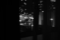 A blurred cityscape at dusk viewed through a rainy window, suggesting reflection and patience.