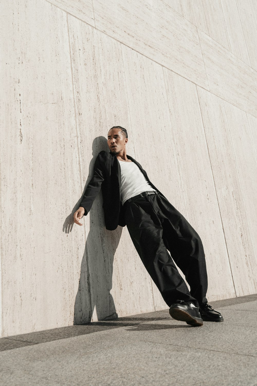 a man leaning against a wall with his arms stretched out