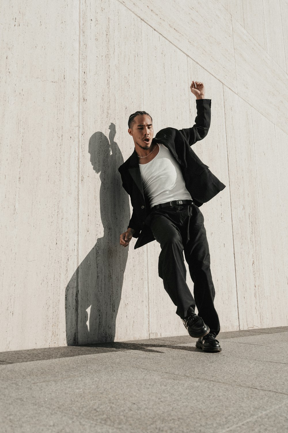 a man leaning against a wall with his shadow on the wall