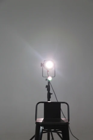 A warm spotlight illuminating an empty actor’s chair on a dark stage.