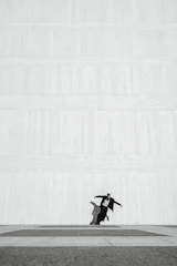A minimalist frame of a solitary figure against a dark, textured wall.