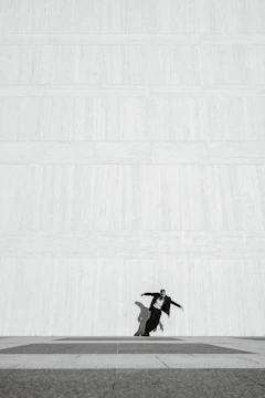 A minimalist frame of a solitary figure against a dark, textured wall.